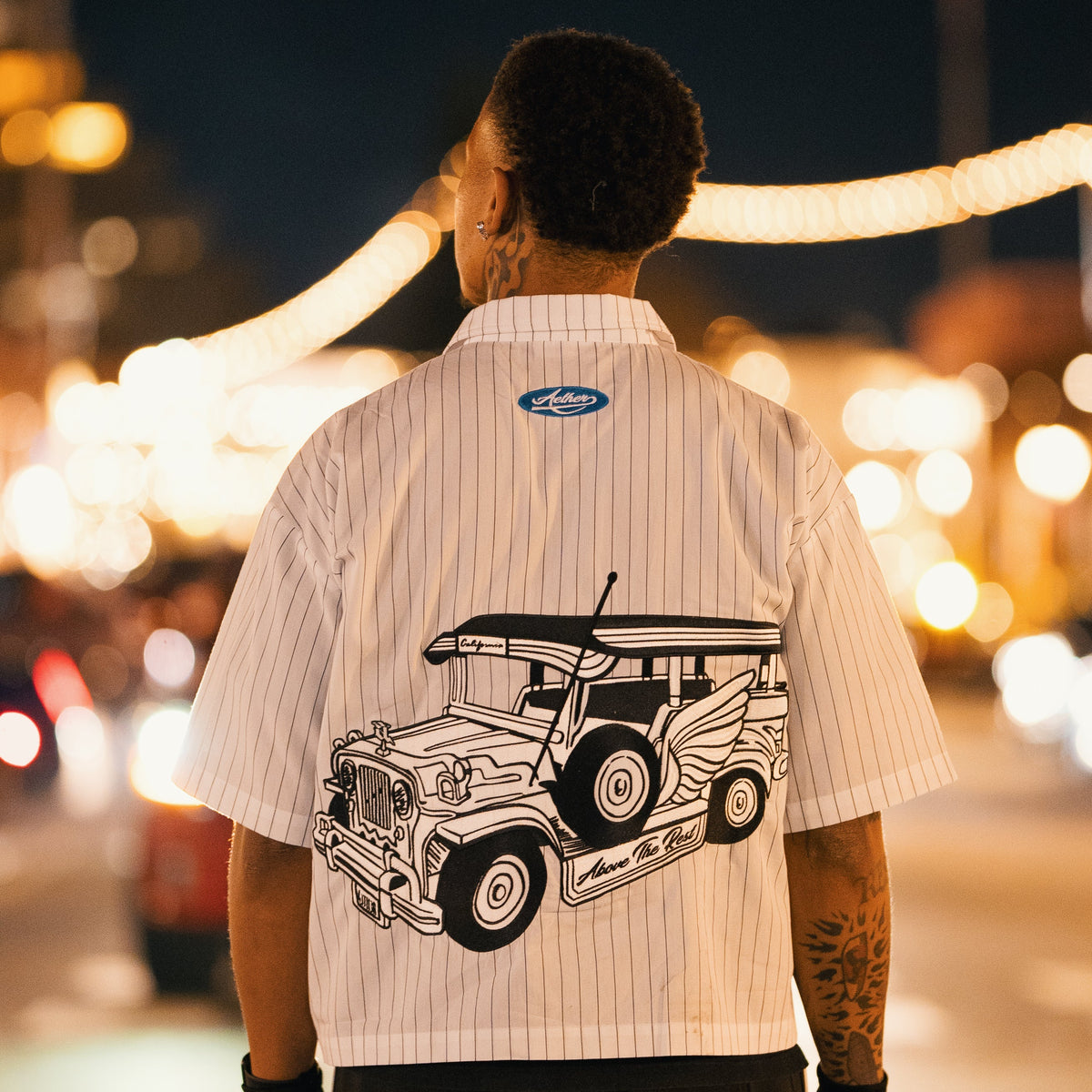 Person wearing a shirt with a graphic of a jeepney on a blurred street background